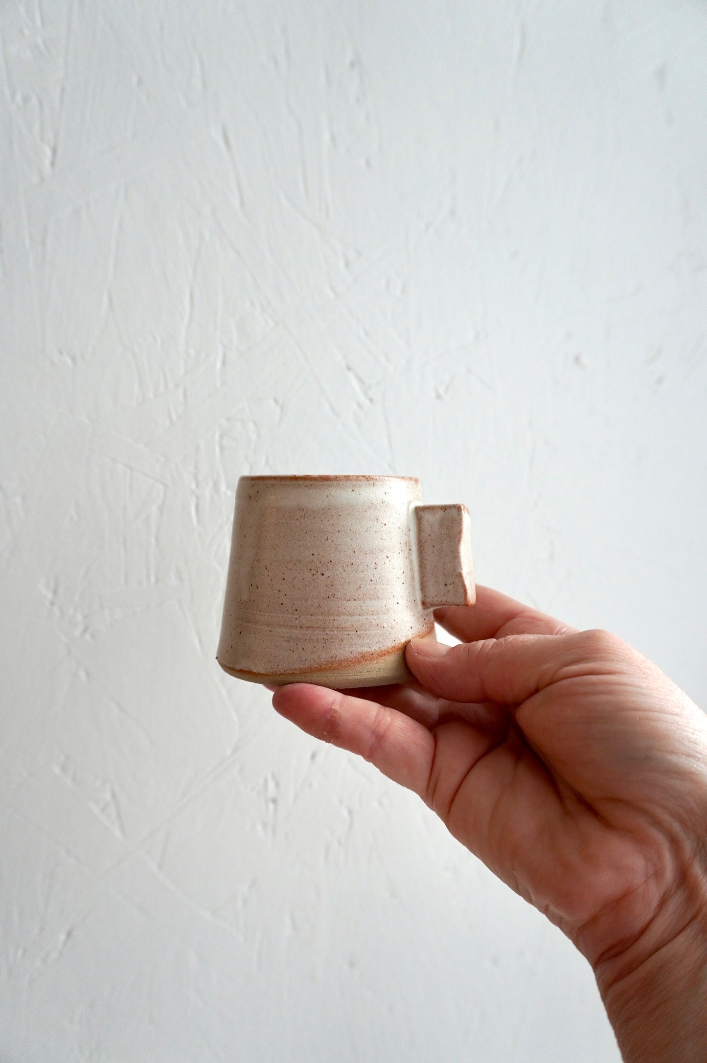 Tasse à espresso en grès émaillé gris, façonnée à la main et présentée dans une main.