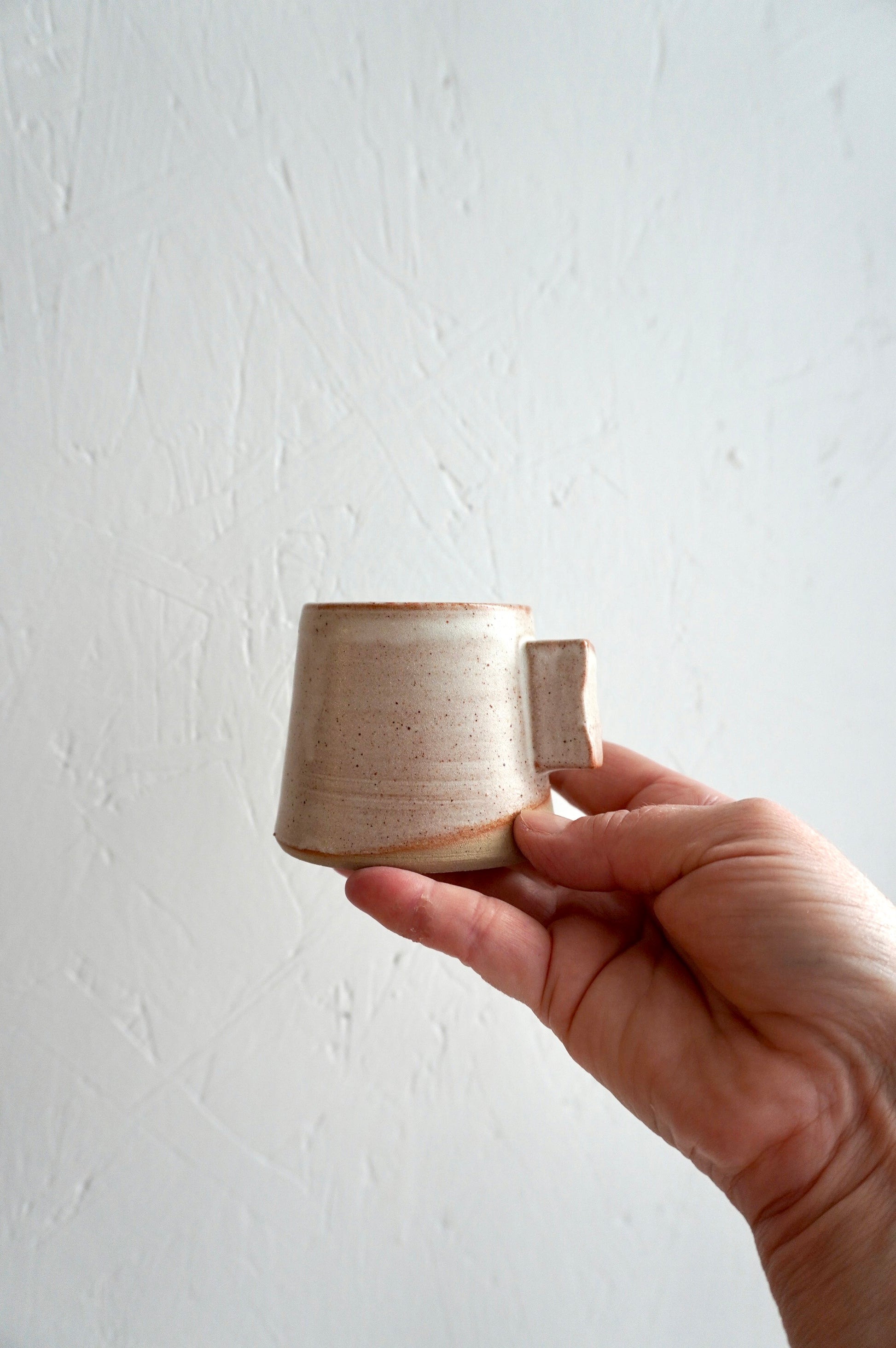Tasse à espresso en grès émaillé gris, façonnée à la main et présentée dans une main.