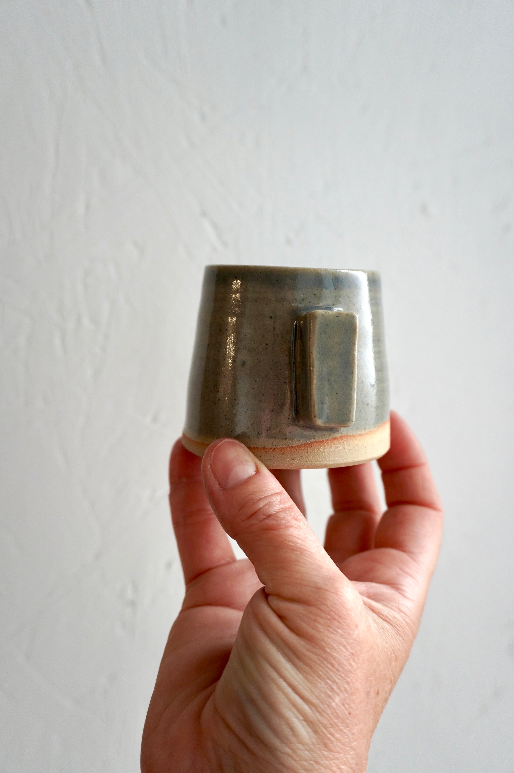 Tasse à espresso en grès émaillé gris, façonnée à la main et présentée dans une main.